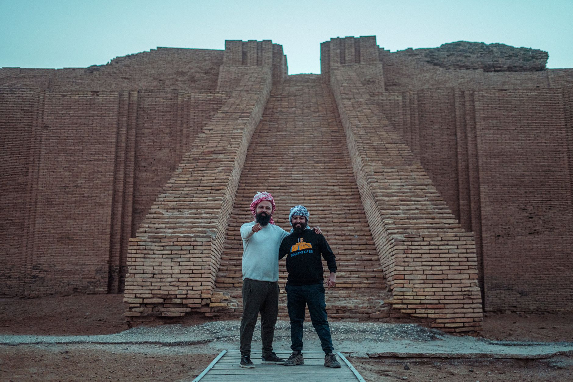 Two tourists pose at the ancient Ziggurat of Ur, a historical landmark in Iraq.