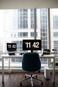 A contemporary office setup featuring dual monitors, sleek furniture, and a cityscape background.