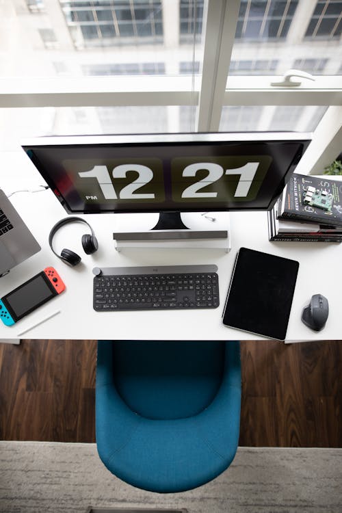 Free A top view of a modern desk setup featuring a computer monitor, keyboard, tablet, books, and gadgets. Stock Photo