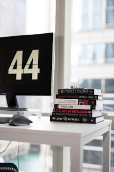 A sleek office desk with stacked books and a monitor displaying '44'.