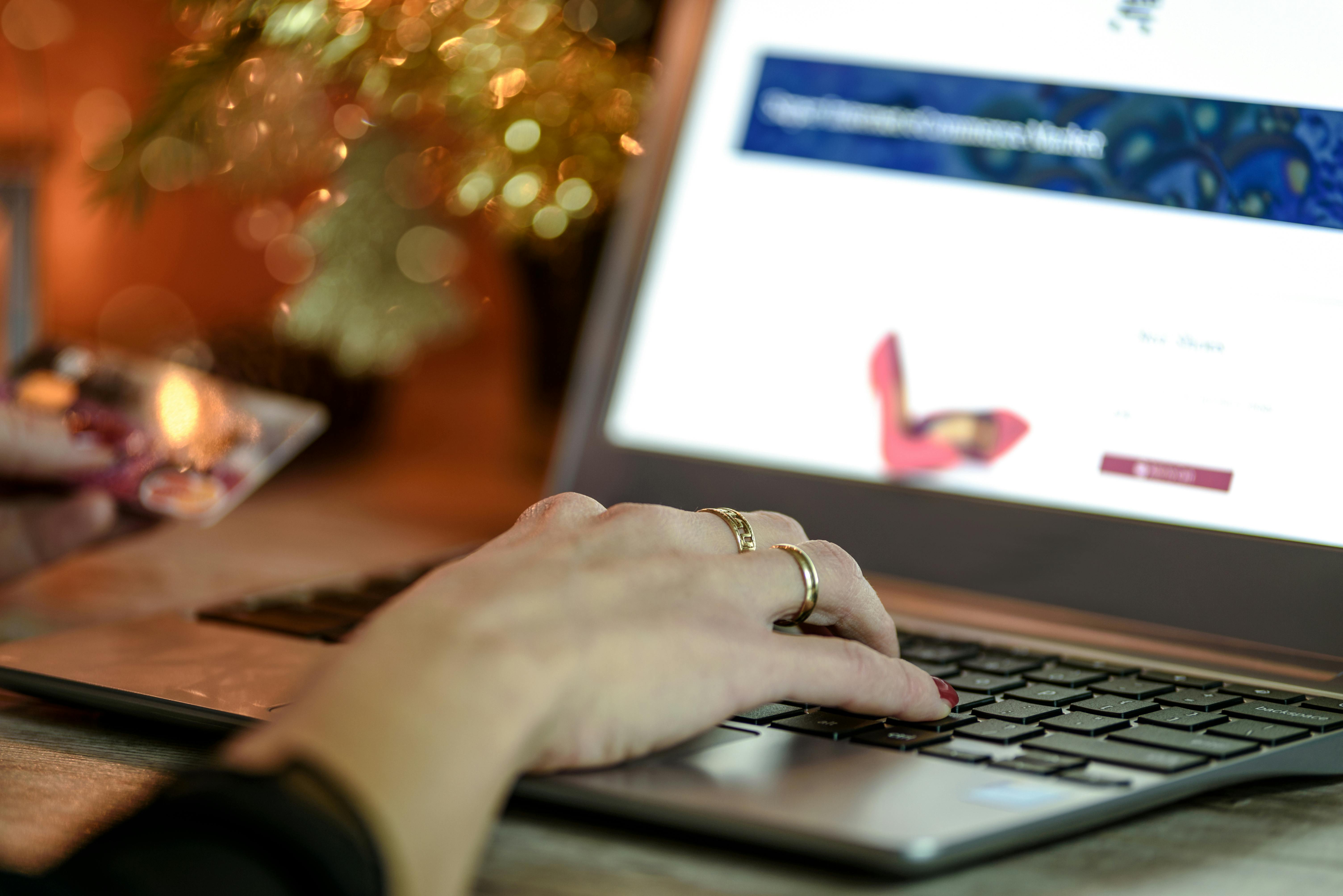 right hand with gold ring on black and grey laptop computer