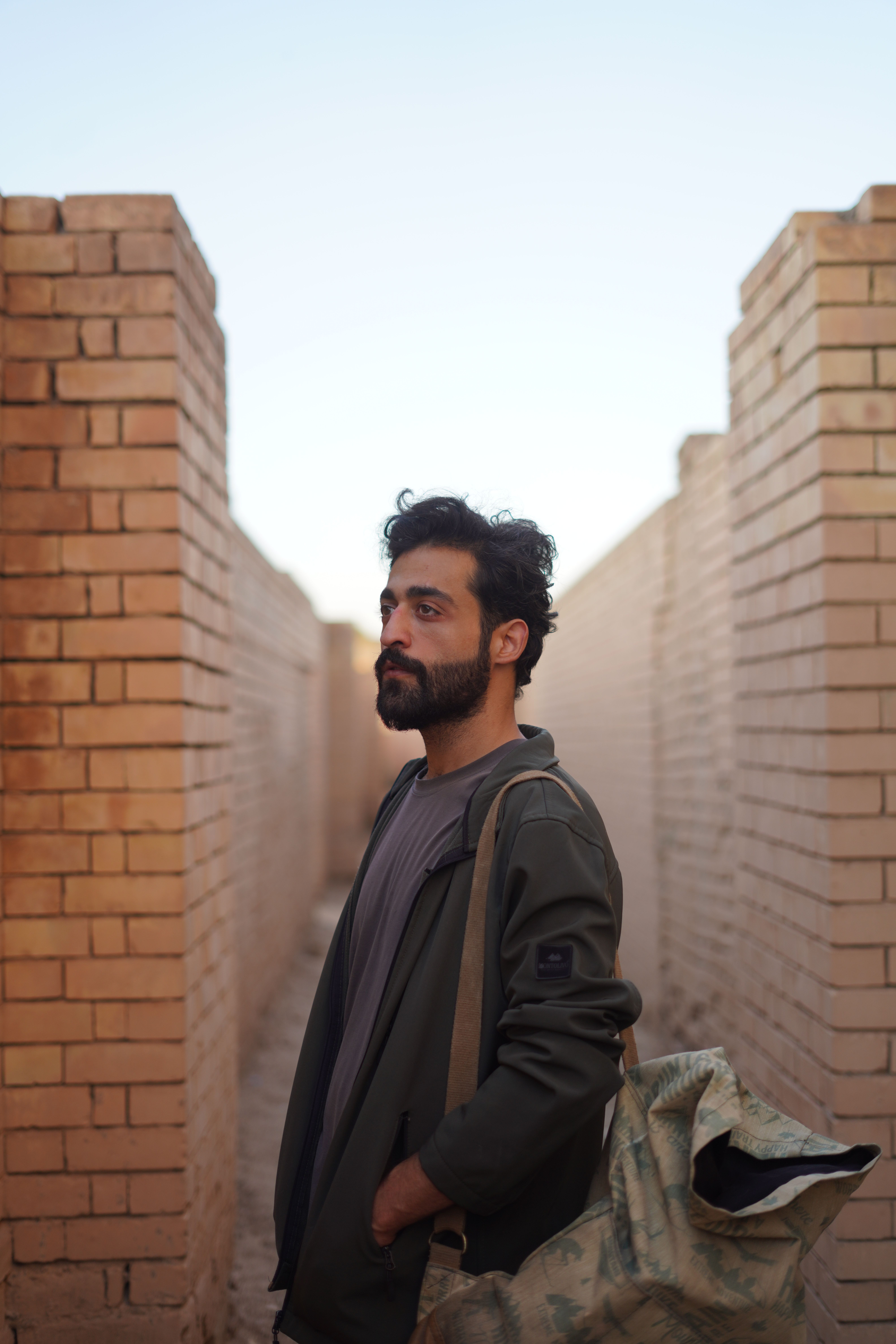 A man stands between ancient brick walls in Baghdad, showcasing historical travel.