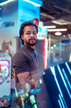 Atmospheric portrait of a man in a Tokyo arcade, showcasing neon lights and reflective surfaces.
