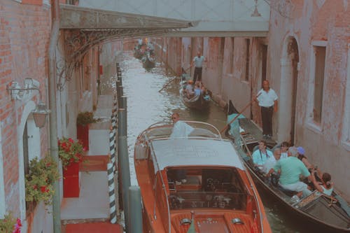 A gondola is in a narrow canal with people on it
