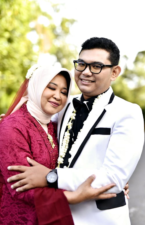 A man and woman in wedding attire pose for a photo