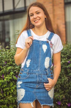 一位在城市环境中穿着牛仔工作服微笑的年轻女子肖像