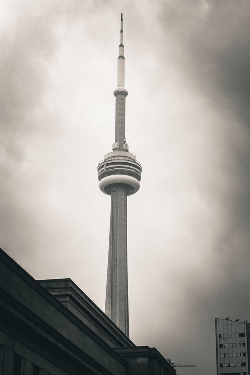Free A striking view of Toronto's CN Tower piercing through a dramatic cloudy sky. Stock Photo