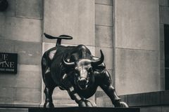 Black and white image of the Charging Bull statue in a cityscape, symbolizing strength and finance.