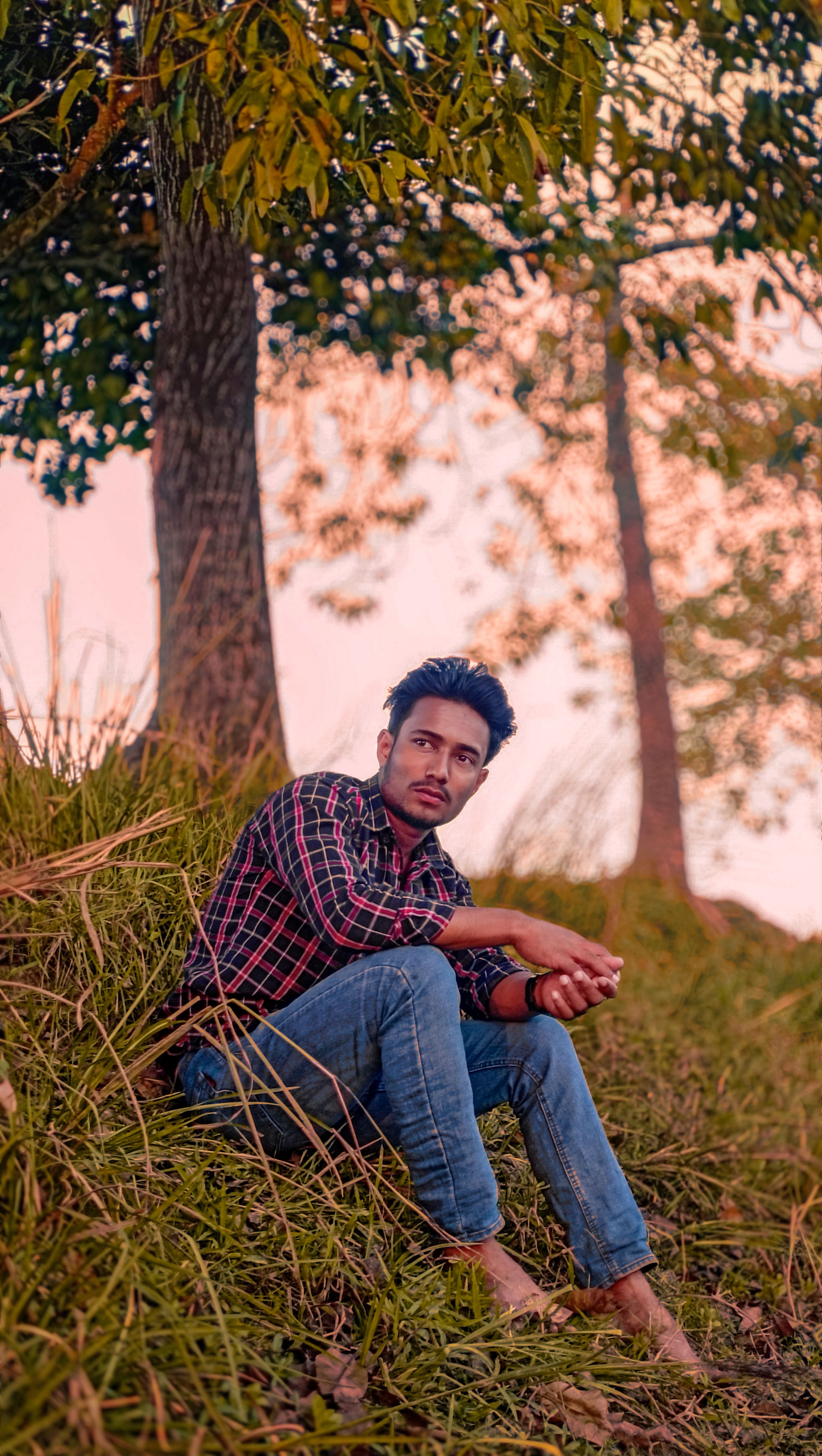 Casual portrait of a man sitting in an autumn forest setting, showcasing fashion and tranquility.