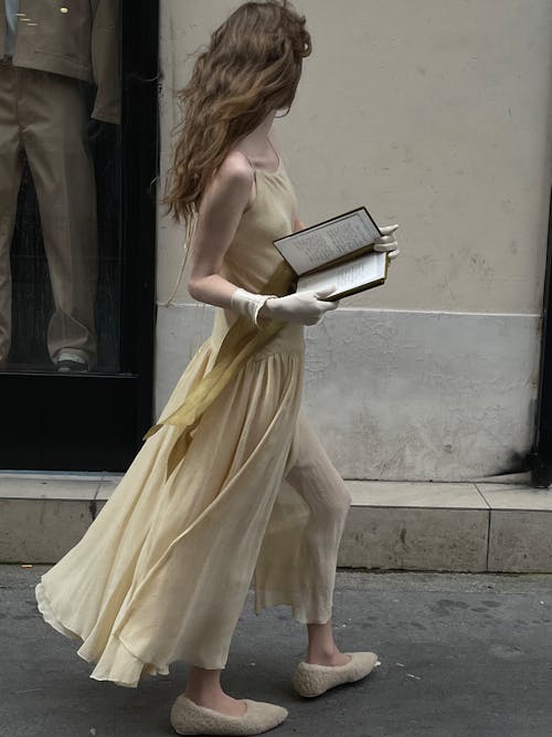 A woman in a yellow dress holding a book