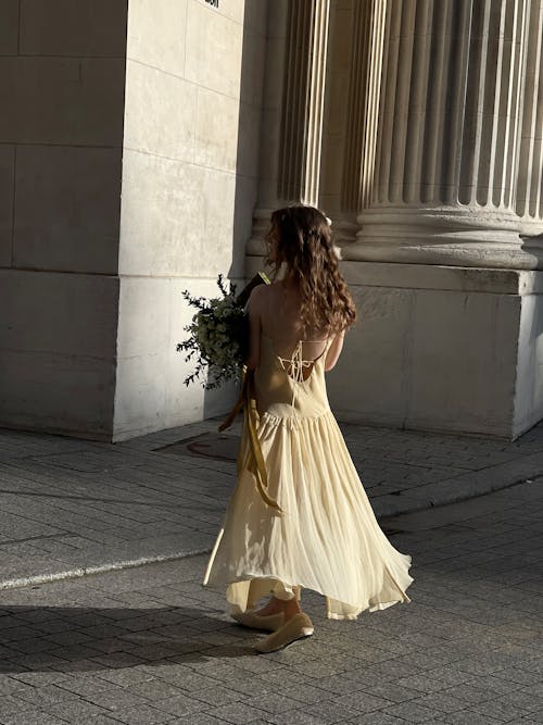 A woman in a yellow dress walks down the street