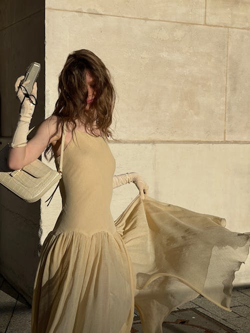 A woman in a yellow dress holding a cell phone