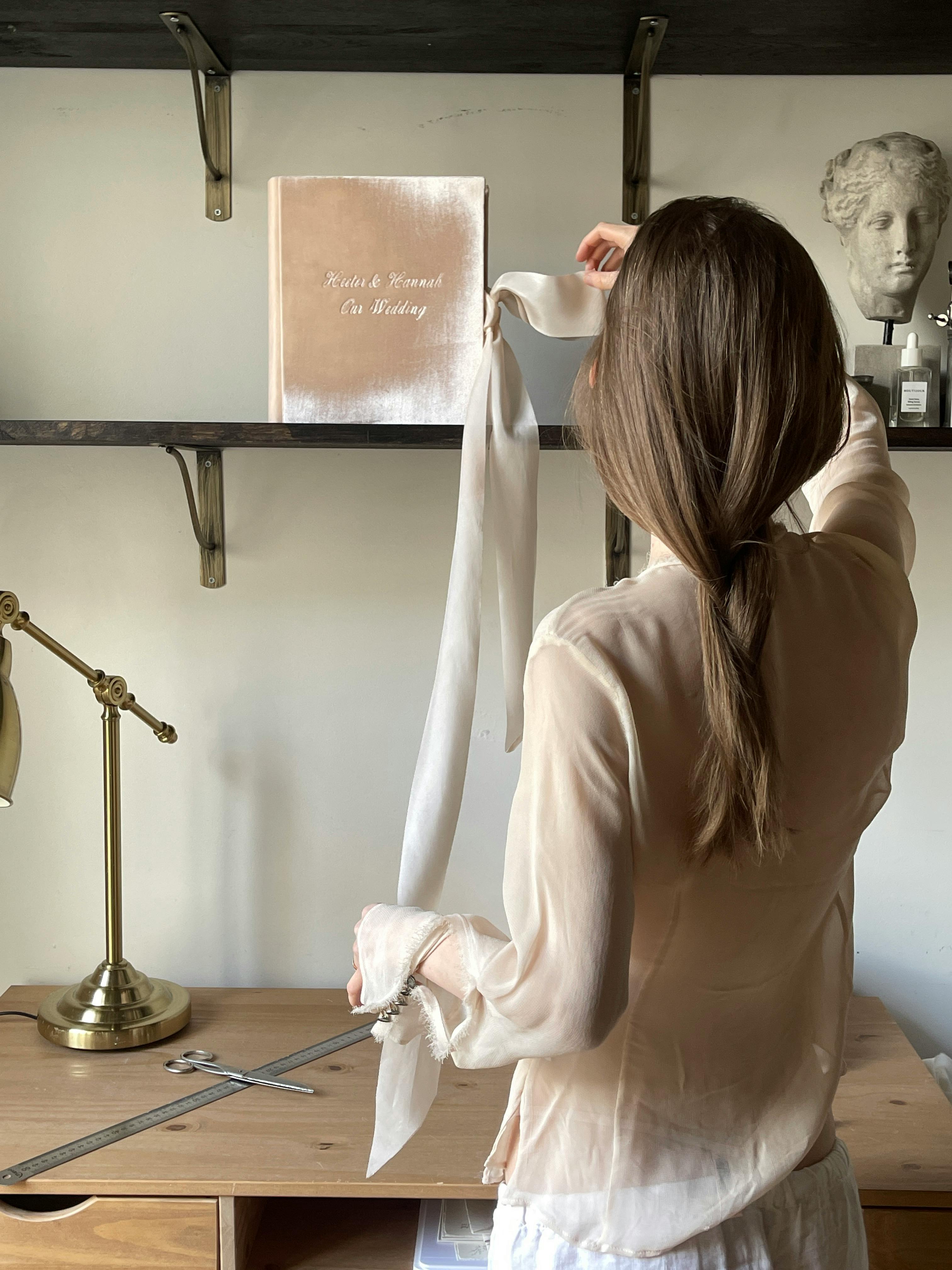 A woman arranging a decorative item on a shelf in a modern interior room.