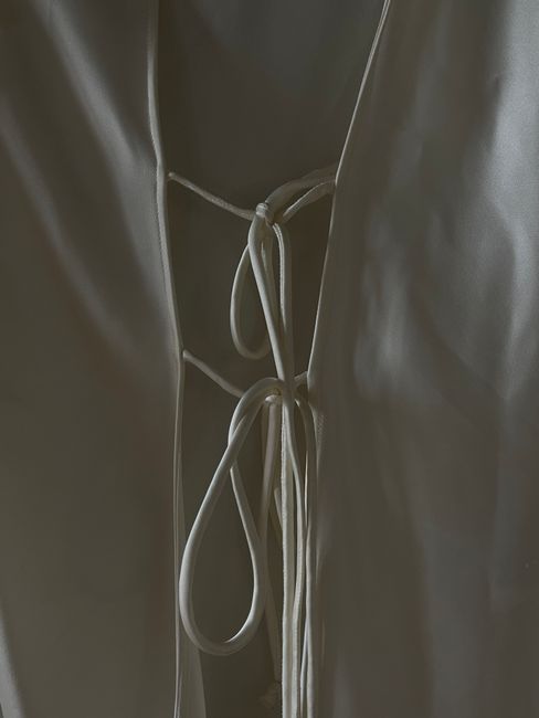Detailed view of satin fabric with tied strings, highlighting texture and elegance.