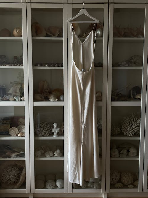 A white dress hanging in a glass case