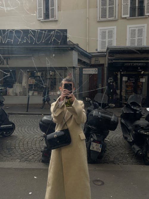 A woman in a beige coat taking a selfie