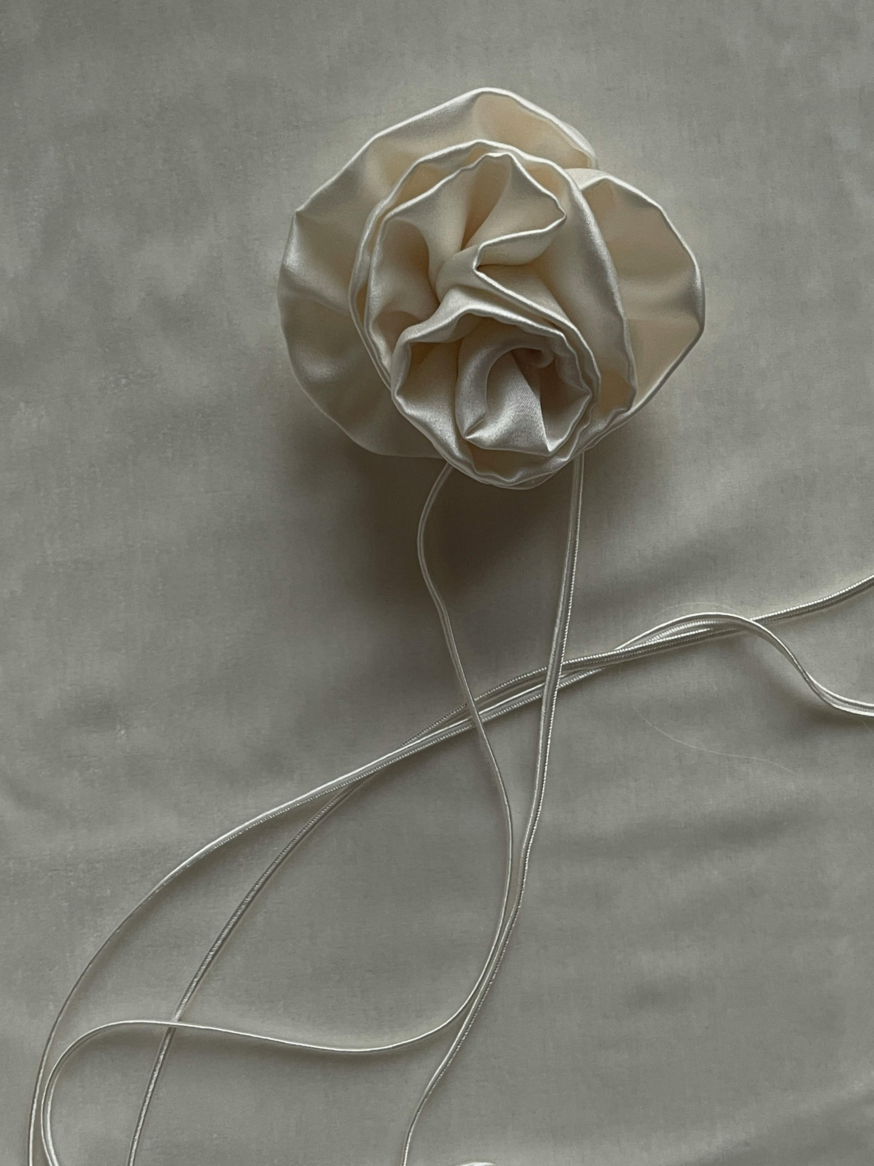 Delicate silk rose on textured fabric, showcasing elegance and softness in a minimalist design.