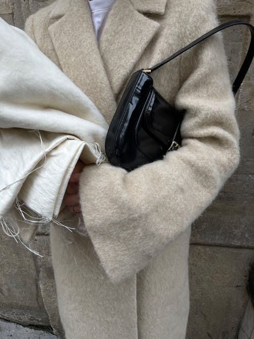 A woman in a beige coat holding a purse