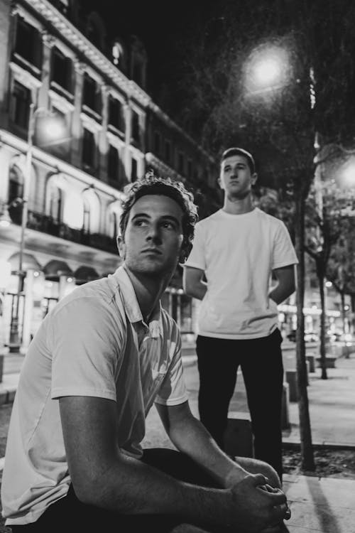 Two men sitting on the street in black and white