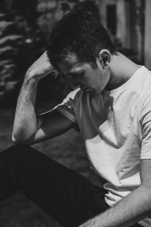 A man sitting on the ground with his hands on his head