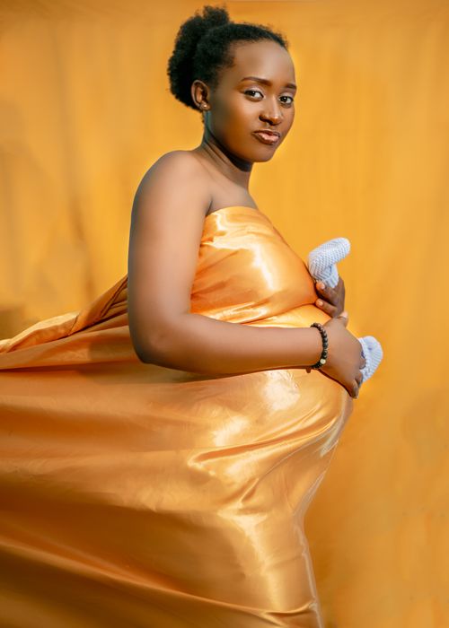 Free Fashionable studio portrait of a pregnant woman in a yellow dress with a matching background. Stock Photo