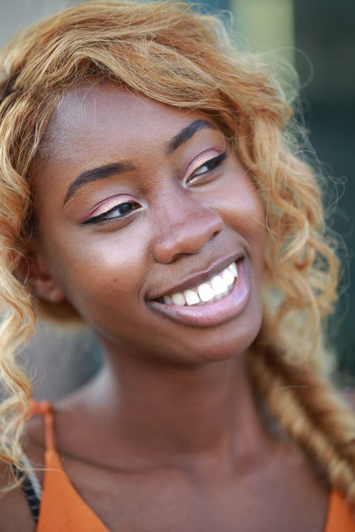 Free Close-up portrait of a smiling woman with blonde dyed hair and radiant skin captured outdoors. Stock Photo