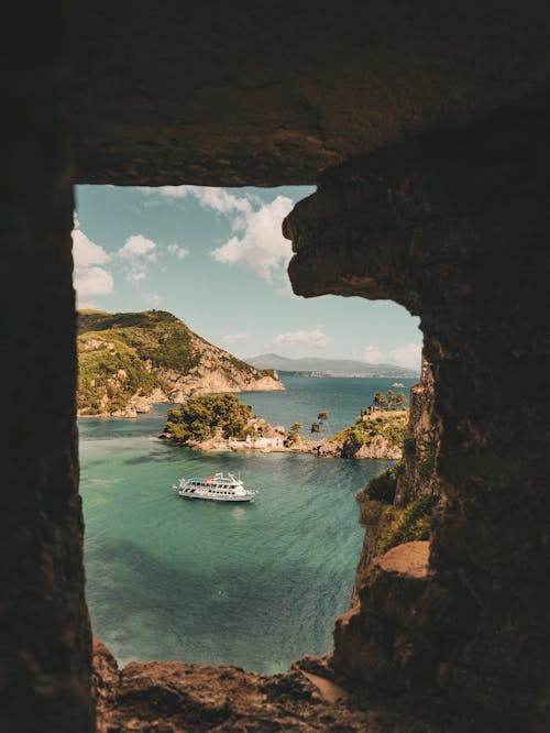 A boat is seen through a window in a cave