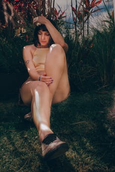 一名女子身着时尚服装，在绿意盎然的花园草地上随意摆着姿势