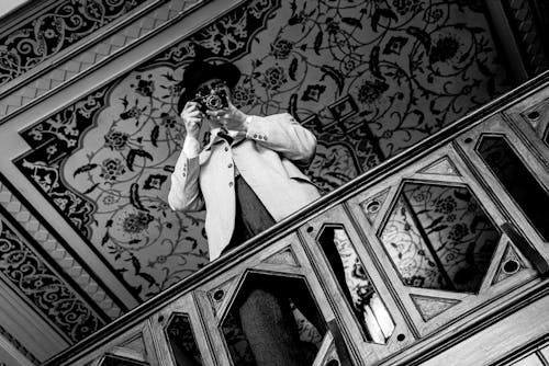 A man in a suit and hat is standing on a balcony