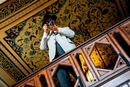 A man in a suit taking a picture on a balcony