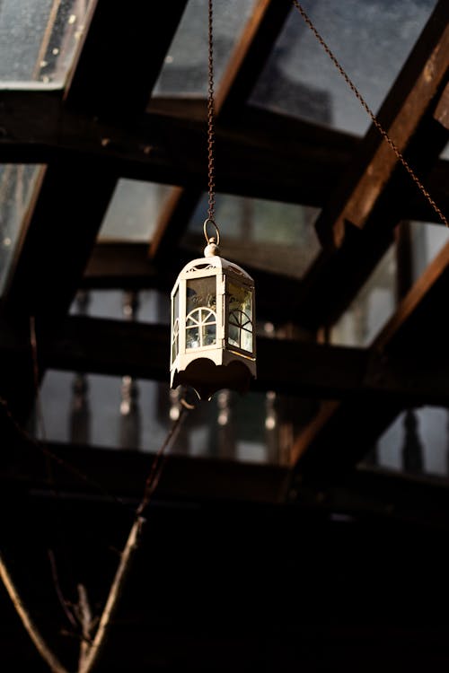 A lantern hanging from a wooden beam in a building