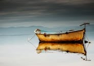 图尔基耶的马尼萨，一艘渔船在平静的水面上倒影，天空多云