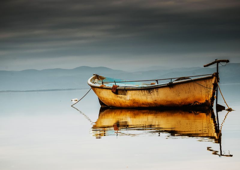 A fishing boat reflected on still water at first light — photo by Korhan Erdol on Pexels