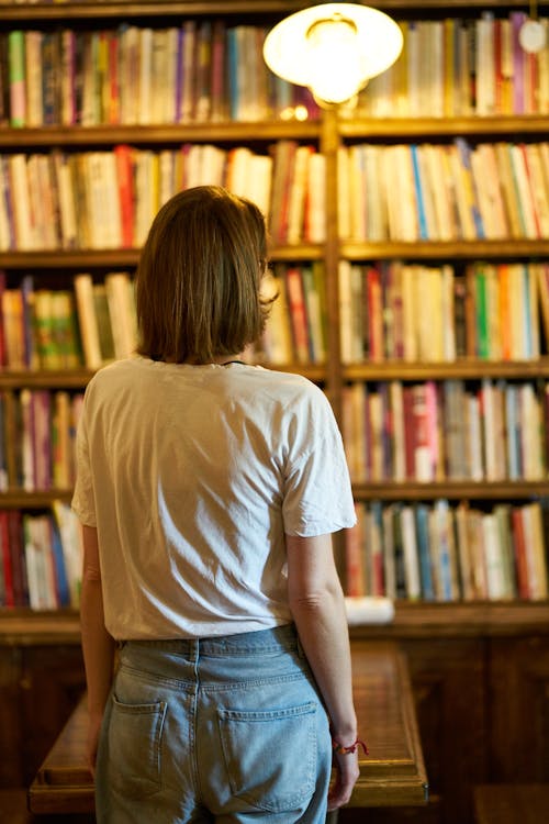 Woman Standing Near Brown Bookshelf