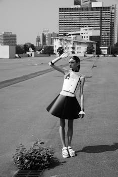 Stylish female model in a futuristic outfit poses outdoors with a city skyline backdrop.