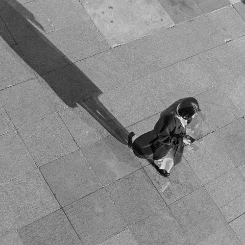 Free A black and white top view of a person walking in an urban setting. Stock Photo
