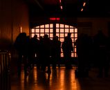 Silhouetted travelers stand by a backlit window at Istanbul terminal, creating a dramatic scene.