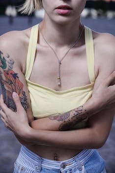 一名身穿黄色上衣的纹身女子站在海滨，镜头给了她一个特写