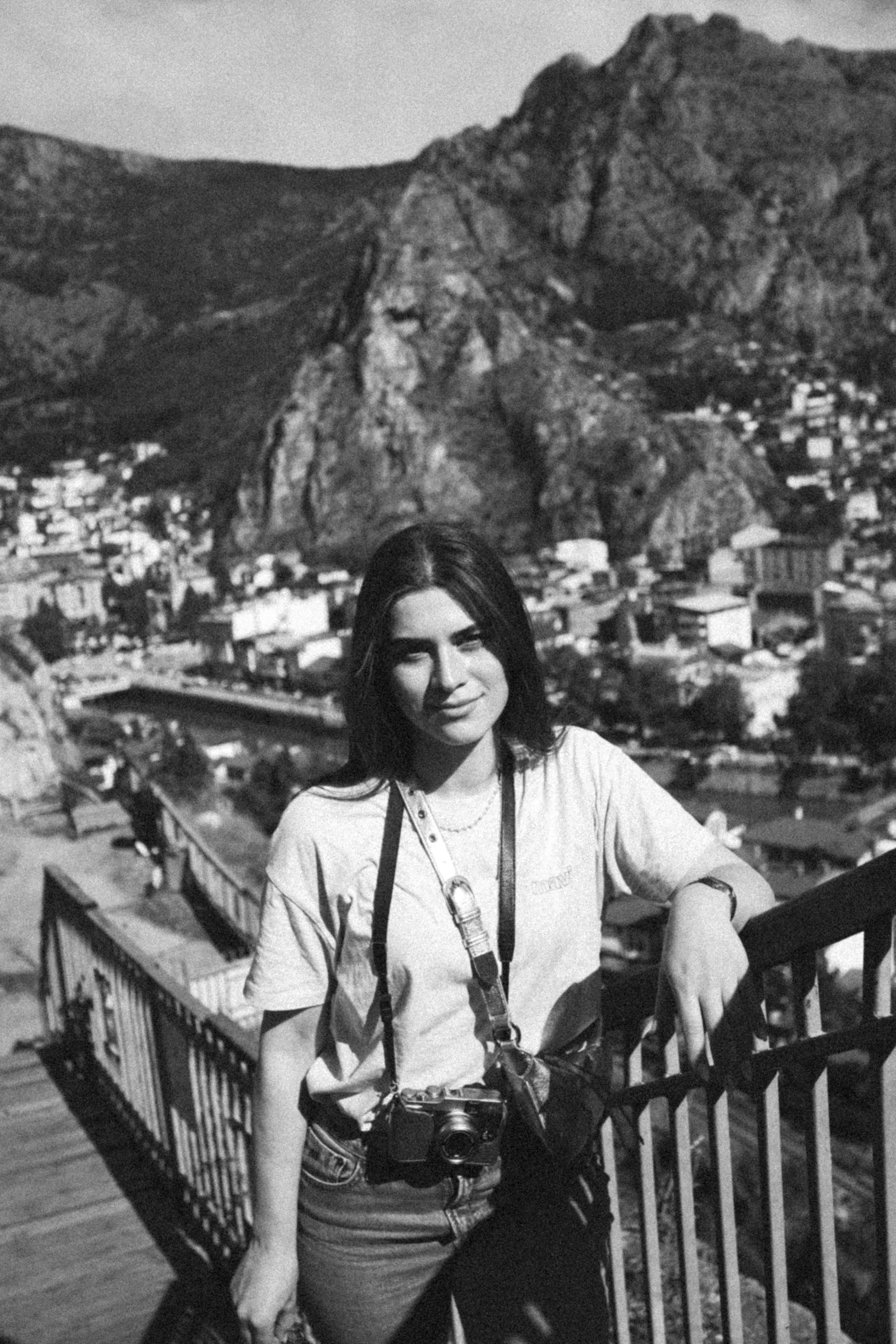 Black and white portrait of a woman standing with a camera in Amasya, Türkiye.