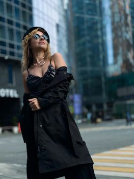 Stylish woman in sunglasses posing confidently in a modern cityscape.