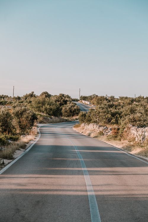 Free Discover the serene beauty of an empty rural road winding through the Croatian countryside under a clear summer sky. Stock Photo