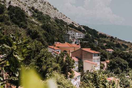 Free Picturesque hillside village featuring red rooftops surrounded by lush greenery. Stock Photo