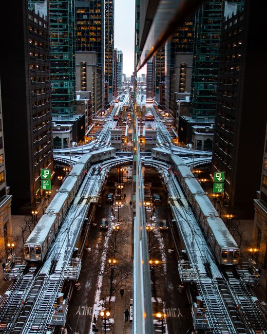 Evening cityscape of Chicago featuring illuminated train tracks amidst skyscrapers, reflecting urban life.
