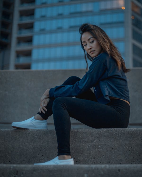 Woman Sitting on Concrete Pavement