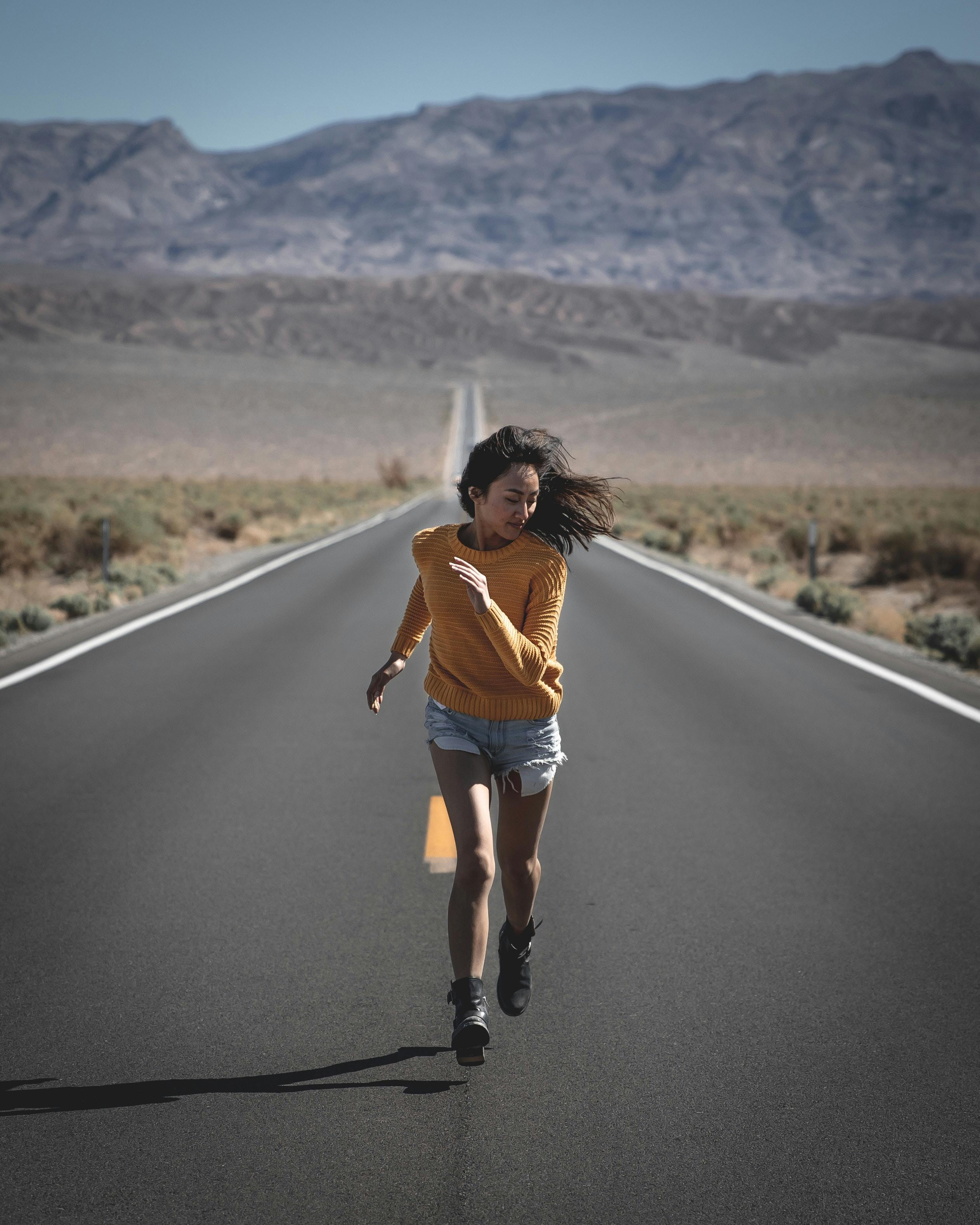 Mujer corriendo hacia el lado de la carretera. paso, carrera y