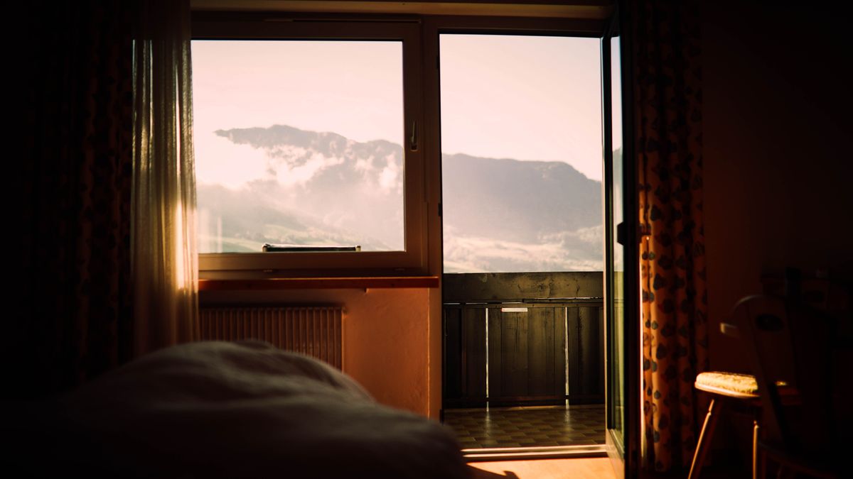 A cozy bedroom with a stunning mountain view through the window at sunset.