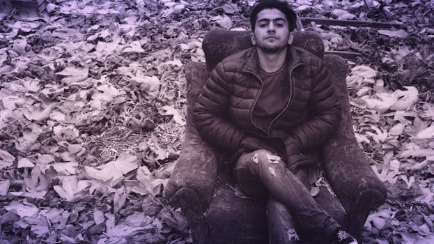 Man in Black Puffer Jacket and Distress Jeans Sitting in Couch