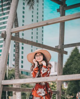 在夏天的背景下，一位快乐的女人穿着花卉连衣裙、戴着太阳帽摆姿势