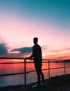在克罗地亚梅杜林，日落时分，一个人的剪影站在栏杆旁，俯瞰着海洋