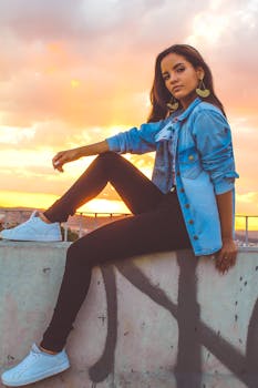 日落时分，一位身穿休闲城市服装的年轻女子在城市屋顶上摆姿势